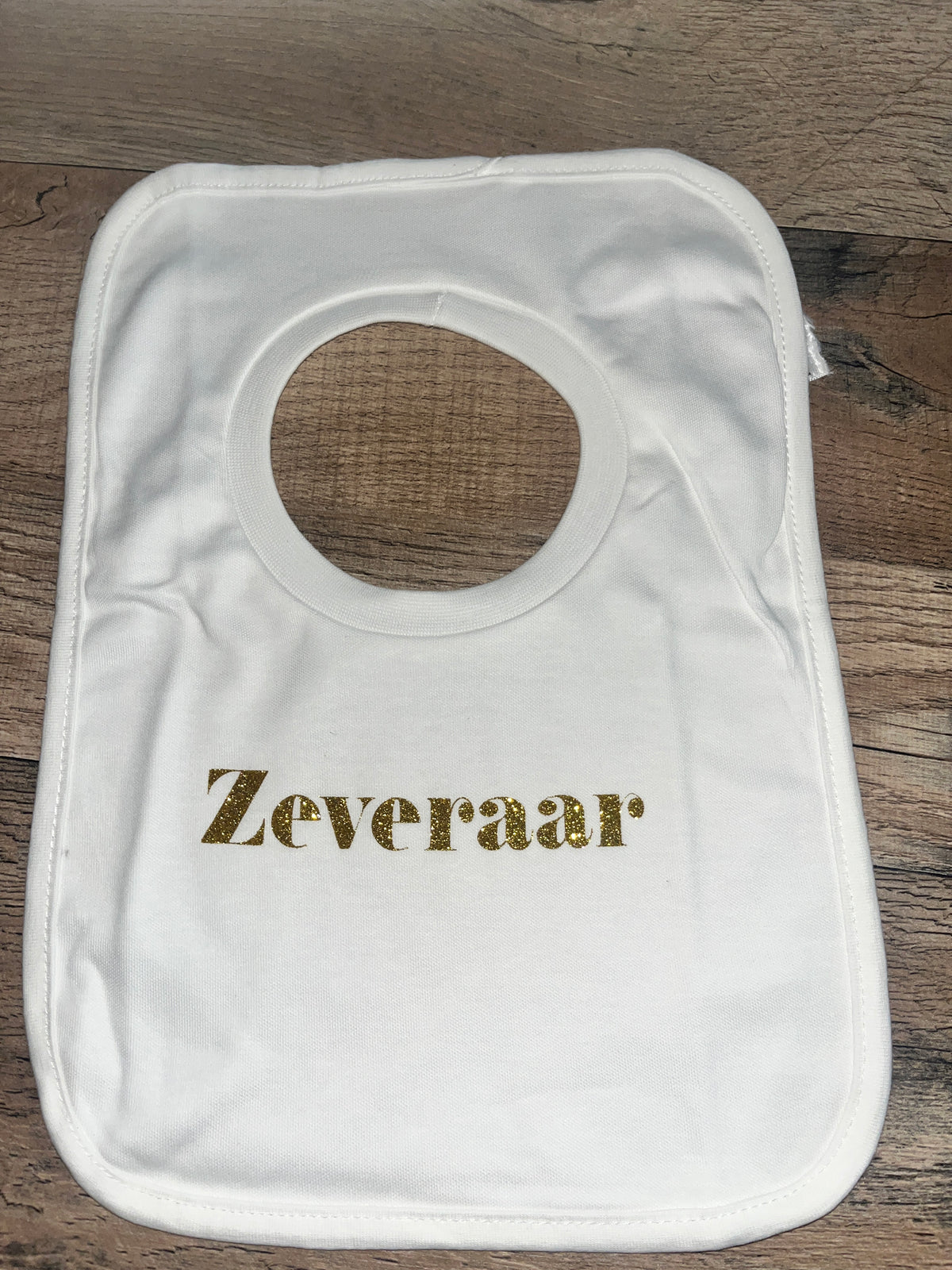 Wit babyslabbetje met goudkleurige glittertekst Zeveraar