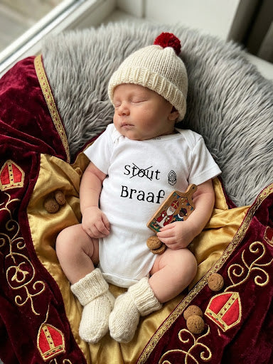 Baby draagt wit rompertje met opdruk Stout doorgestreept en Braaf