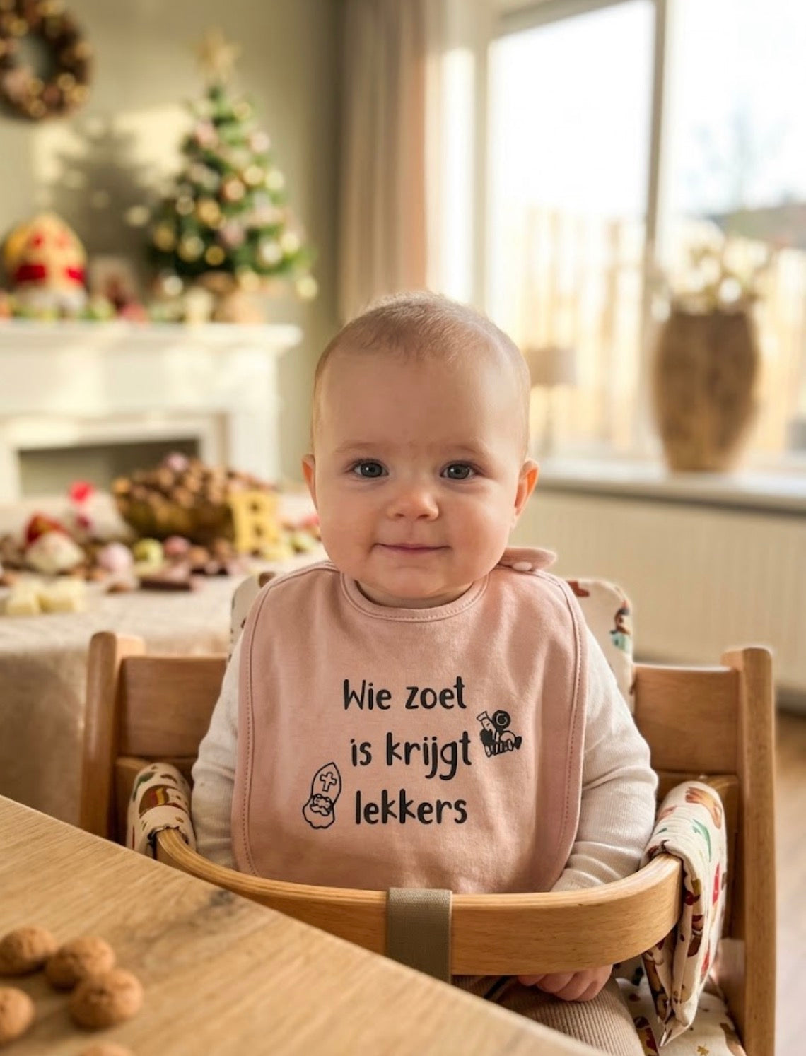 Baby draagt lichtroze slabbetje met tekst Wie zoet is krijgt lekkers