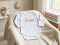 Witte babyromper met lange mouwen en roze glittertekst Zusje