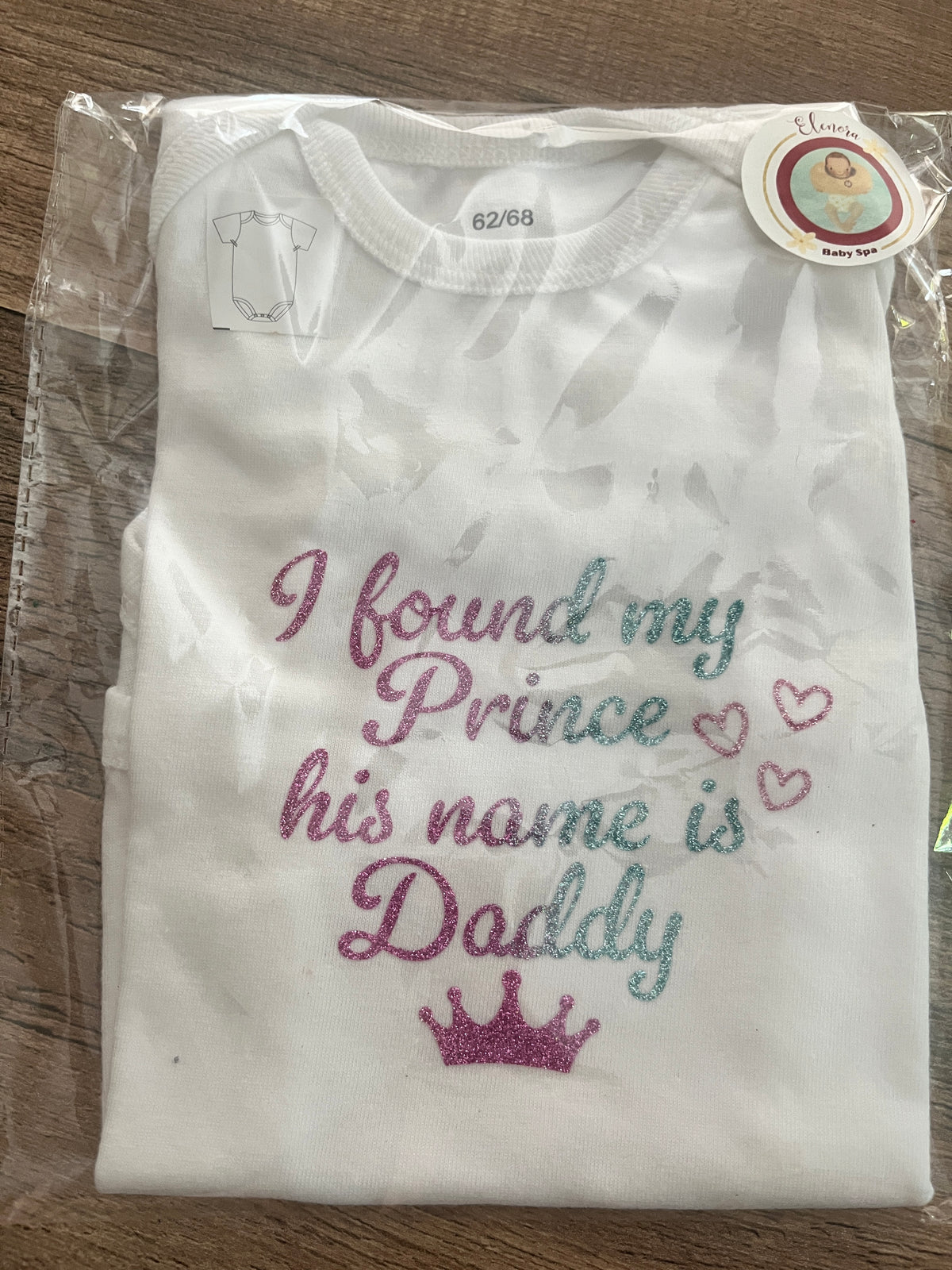 Opgevouwen witte babyromper met Prince Daddy-print in doorzichtige verpakking